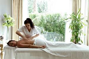 Eine Frau im weißen Kleid führt eine Massage an einem Mann im Zafiro Tropic Hotel durch.