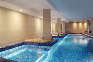 Innenpool des Zafiro Tropic Hotel mit blauem Wasser und weißen Wänden.
