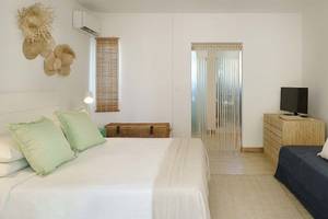 Schlafzimmer im The Ravenala Attitude Hotel mit weißen Wänden, einem großen Bett, grünen Kissen und einer Couch.