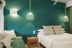 Schlafzimmer im The Ravenala Attitude Hotel mit grünen Wänden, zwei Betten und Lampen