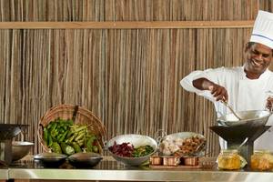 Ein Koch bereitet eine Mahlzeit im The Ravenala Attitude Hotel zu, umgeben von Zutaten und Küchenutensilien.