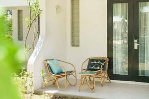 Der Vorgarten des Ravenala Attitude Hotels mit zwei Rattan-Stuhl, einem kleinen Tisch und einem schwarzen Eingangstor.