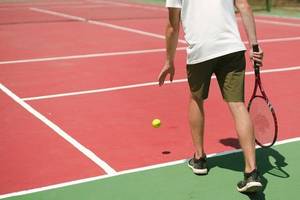 Ein Tennisspieler auf einem roten Tennisplatz, bereit, einen Ball zu schlagen.