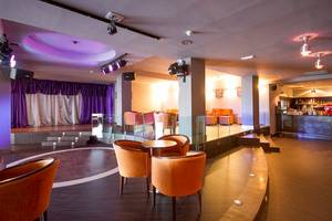 Innenbereich des Lanzarote Village Hotels mit orangefarbenen Stühlen und einer Bühne.