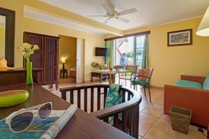 Wohnzimmer im Pierre & Vacances Village Sainte Luce mit gelben Wänden, einer Deckenventilator, einem Tisch und Stühlen.