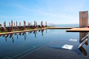 Poolterrasse des Riviera Vista Hotels mit Sonnenliegen und Schirmen am Meer