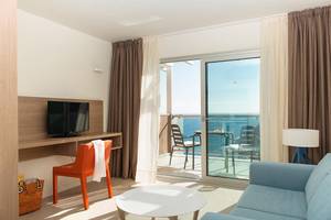 Zimmer mit Meerblick im Riviera Vista Hotel, ausgestattet mit Fernseher, Schreibtisch und Balkonmöbeln.