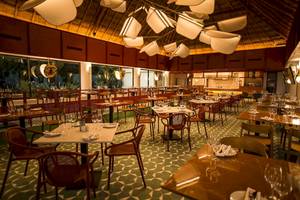 Innenansicht des Restaurants im Bahia Principe Luxury Akumal Hotel mit gedeckten Tischen und Stühlen.