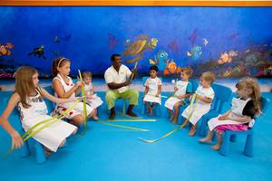 Ein Kurs im Kurumba Maldives mit Kindern und einem Lehrer vor einem blauen Wandbild mit Meerestieren.