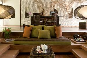 Hotel-Lounge-Bereich mit einem Sofa, grünen Kissen, einem Tisch und einer Tasse Tee auf dem Tisch.
