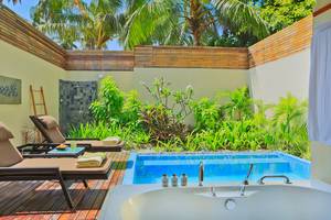 Außenpool und Terrasse im Kurumba Maldives Hotel mit Loungestühlen und Pflanzen.