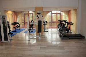 Fitnessraum im Hotel Gaia Village mit verschiedenen Trainingsgeräten und freien Fenstern.