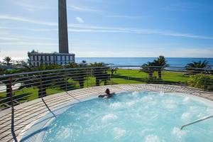 Person in einem Whirlpool auf der Terrasse mit Blick auf den Ozean