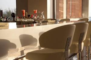 Hotelbar mit Sitzgelegenheiten, Blick auf das Meer und verschiedene Getränkeflaschen auf dem Tresen.