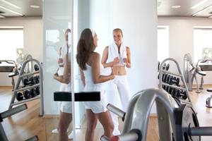 Fitnessstudio im Sentido Port Royal Villas & Spa mit zwei Frauen, die sich gegenseitig anfeuern.