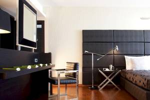 Schlafzimmer im Sentido Port Royal Villas & Spa Hotel mit schwarzem Kopfteil, Schreibtisch und Nachttisch.