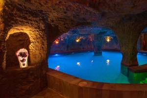 Unterirdischer Pool im Lopesan Costa Meloneras Resort & Spa mit farbigen Lichtern und Steinwand.
