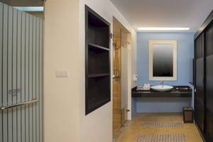 Badezimmer des Anyavee Tubkaek Beach Resort mit blauen Wänden, einem Waschbecken, Spiegel und offenen Schrank.