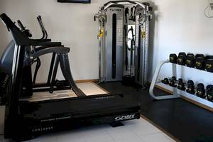 Fitnessstudio im Nova Maldives Hotel mit Laufband, Hanteln und Kraftgeräten.