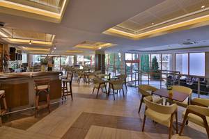Innenbereich der Bar im Kaliakra Beach Hotel mit Holzboden, Tischen, Stühlen und einer Theke.