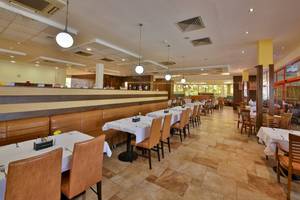 Innenansicht des Restaurants im Kaliakra Beach Hotel mit gepolsterten Bänken und Tischen.