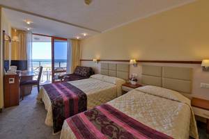 Doppelzimmer im Kaliakra Beach Hotel mit Balkon und Meerblick, zwei Betten, Schreibtisch, Fernseher und Fenster mit Blick auf das Meer.
