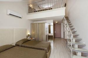 Doppelzimmer mit Balkon im Calimera Hane Garden Hotel, mit zwei Betten, Klimaanlage, und einer Treppe zur oberen Etage.