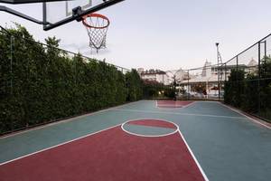 Basketballplatz im Calimera Hane Garden Hotel mit umzäunten Bereich und Gebäude im Hintergrund.