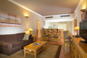 Wohnbereich des Millennium Plaza Downtown Hotels mit Sofa, Couchtisch, Fernseher und Esstisch.