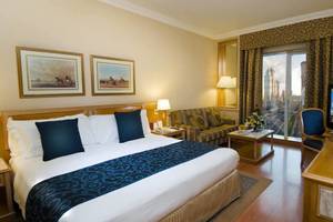 Hotelzimmer im Millennium Plaza Downtown mit Bett, Sofa, Fernseher und Stadtblick.