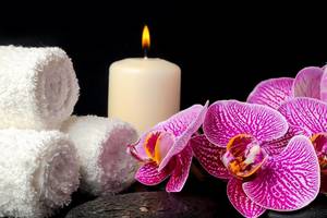 Spa-Einrichtung mit Kerze, Orchideen, Handtüchern und Steinen im Millennium Plaza Downtown Hotel