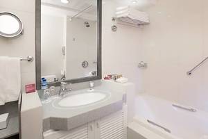Badezimmer im Millennium Plaza Downtown Hotel mit Badewanne, Waschbecken und Spiegel