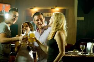 Gruppe lachelnder Leute, die Bier in einer Bar trinken.