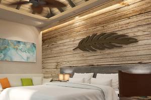 Schlafzimmer mit Holzwand im You & Me Maldives Hotel, Bett mit weißen Laken, Kissen und Decken.