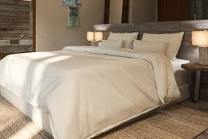 Schlafzimmer im You & Me Maldives Hotel mit weißem Bett und Nachttischen.