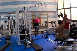 Fitnessraum im Melia Varadero Hotel mit Geräten und einem Mann, der Gewichte hebt.