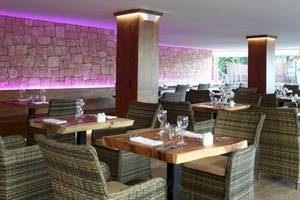 Innenansicht des Restaurants im Sandos El Greco Beach Hotel mit steinerner Wand und lila Beleuchtung.