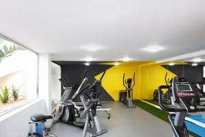 Fitnesscenter-Innenbereich im Sandos El Greco Beach Hotel mit Cardiogeräten und einer Fensteransicht.