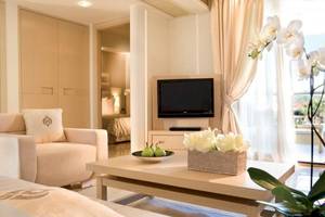 Wohnzimmer des Porto Sani Hotels mit Fernseher, Sofa, Tisch und Blumen.