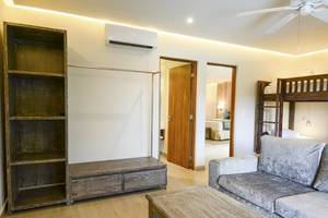 Wohnzimmer im Sandos Caracol Eco Resort mit Sofa, Couchtisch, Bücherregal und Klimaanlage.