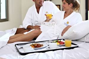 Ein Paar genießt das Frühstück im Bett im Sandos Caracol Eco Resort.