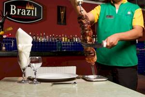Ein Mitarbeiter schneidet Fleisch im Brazilian Rodizio Restaurant.