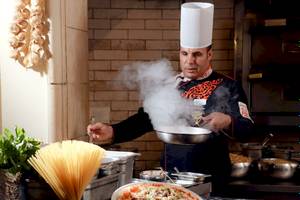Koch im LABRANDA Royal Makadi Hotel, der eine Pizza zubereitet und Nudeln kocht.
