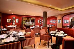 Innenbereich eines Restaurants im Jaz Aquamarine Resort mit roten Wänden, Tischdecken und Fotos an der Wand.