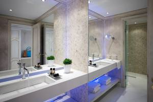 Badezimmer im Mitsis Laguna Resort mit zwei Waschbecken, Spiegeln und einer Glasdusche.