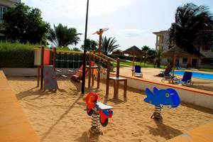 Sandkasten im Freibereich des Agua Hotels Sal Vila Verde mit Spielgeräten und Gebäude im Hintergrund.