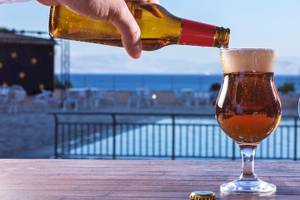Hand gießt Bier in ein Glas im Aeolos Beach Resort auf Korfu