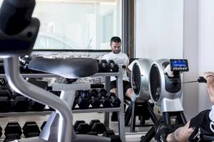 Zwei Männer im Aeolos Beach Resort auf Korfu nutzen Fitnessgeräte im Fitnessstudio.