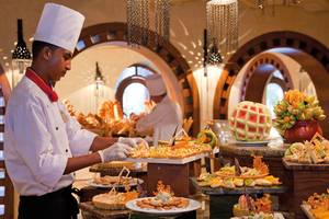 Ein Koch im Ghazala Gardens Hotel serviert eine Auswahl an Gerichten auf dem Buffettisch.