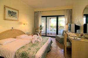Doppelbett im Hotelzimmer Ghazala Gardens mit geschwungenem Kopfteil und zwei Schwanenfiguren auf der Bettdecke.